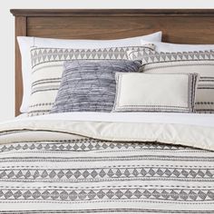 a bed topped with pillows and blankets next to a wooden headboard