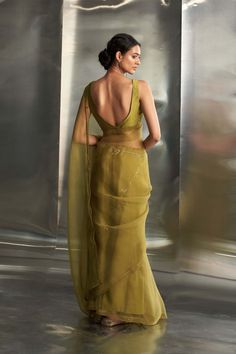 Embrace timeless elegance with this stunning berry green sari, crafted from pure organza fabric. Adorned with intricate golden nakshi hand embroidery inspired by graceful leaf motifs, it exudes richness and vibrancy. The ensemble is completed with a deep-neck, sleeveless padded chanderi blouse, adding a touch of glamour to this sophisticated outfit. Green Saree Blouse Ideas, Sleeveless Golden Blouse, Green Sari Look, Red Saree Green Blouse, Green Saree Blouse Designs, Saree Outfit, Green Sari, Sleeveless Blouse Designs, Sleeveless Blouse Saree