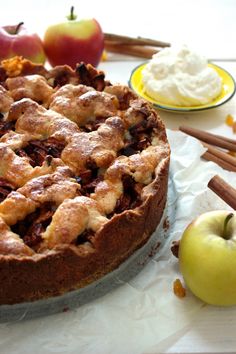 a pie sitting on top of a white table next to an apple and cinnamon stick