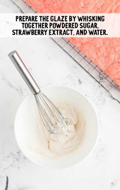 a white bowl filled with whipped cream next to a whisk on top of a counter