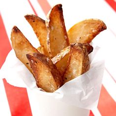 a white cup filled with french fries on top of a red and white table cloth