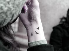 a woman's wrist tattoo with the word together written on her left hand and another person sitting in the background