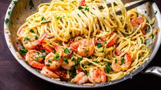 pasta with shrimp and parsley in a skillet on a wooden table top, ready to be eaten