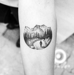 a man's arm with a mountain and forest scene tattoo on the left inner forearm