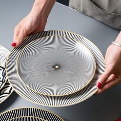 a woman is holding a plate on top of a table with other plates around her