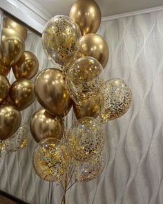 a bunch of balloons that are hanging in the air with gold confetti on them