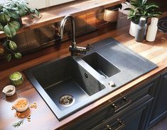 a kitchen sink sitting on top of a wooden counter next to a potted plant