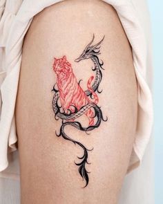 a woman's thigh with a tattoo on it that has a dragon and tiger on it