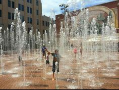 children playing in the water fountains on a sunny day