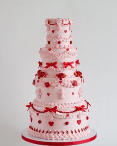 a three tiered wedding cake with red bows and hearts on the top is shown