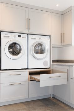 two washers are sitting in the middle of a kitchen with white cabinets and drawers