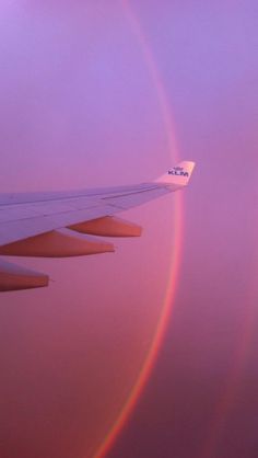 an airplane wing with a rainbow in the background