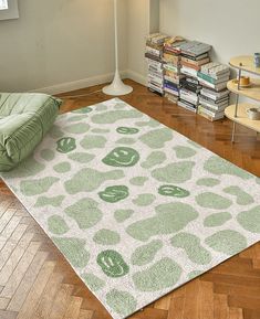 a green and white rug on the floor in front of a lamp with bookshelves behind it