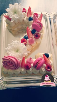 a white cake with pink frosting and strawberries on the number two is decorated with flowers