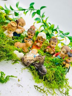 small figurines sitting on top of moss in the shape of people and animals