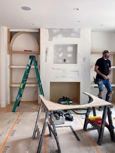 a man standing on top of a wooden table in a room with shelves and ladders