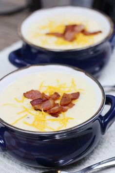 two bowls of soup with bacon and cheese in them sitting on a white table cloth