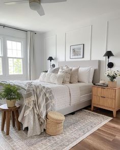 a bedroom with white walls and wood flooring has a large bed, two nightstands, and a rug on the floor