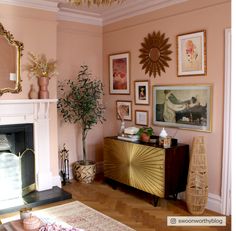 a living room with pink walls and pictures on the wall next to a fire place