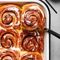 cinnamon rolls in a baking dish with icing drizzled on top, ready to be eaten