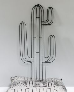 a black and white pillow sitting on top of a bed next to a metal cactus headboard