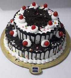 a large black and white cake with cherries on top