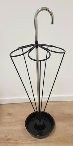 a metal umbrella stand on top of a wooden floor