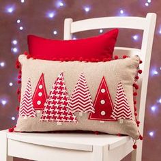 a white chair with a red and white pillow on it next to a christmas tree wallpaper