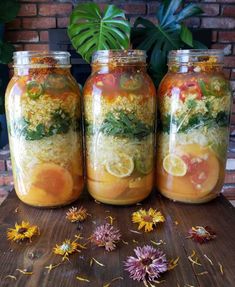 three jars filled with food sitting on top of a wooden table next to some flowers