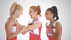 three young women in cheerleader outfits standing next to each other with their hands together