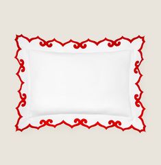 a white pillow with red trim on the edges and an embroidered border at the bottom