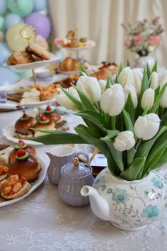 a table topped with lots of plates and cups filled with food covered in white tulips