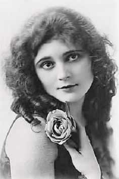 an old black and white photo of a woman with a rose in her hair