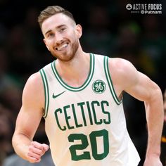 a male basketball player in a green and white uniform is smiling at the camera with his hand on his hip