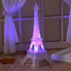 the eiffel tower is lit up with purple lights in front of a window