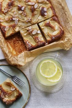 slices of lemon almond cake next to a glass of lemonade and a plate with sliced lemons on it