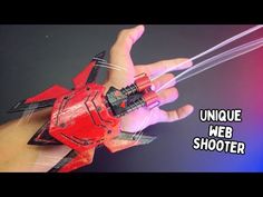 a hand holding a red toy car in it's right hand and the words unique web shooter above it