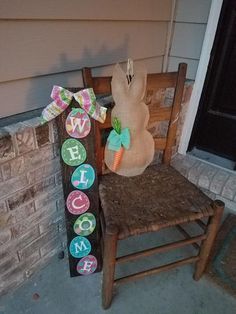 a wooden chair sitting in front of a brick wall next to a sign that says welcome home