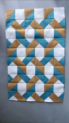 a blue and white quilted piece with gold triangles on the front, sitting on top of a gray surface