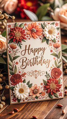 a happy birthday card with flowers and leaves on the table next to some dried flowers