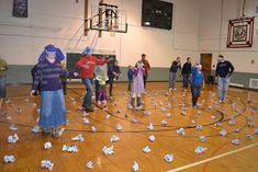 a group of people standing on top of a basketball court covered in paper birds and streamers