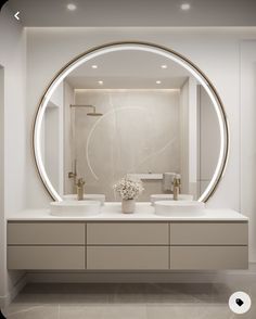 a bathroom with two sinks and a large round mirror