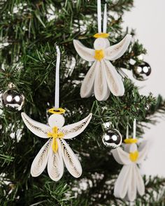 three white angel ornaments hanging from a christmas tree