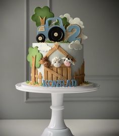 a birthday cake with farm animals and tractor decorations on the top is sitting on a pedestal