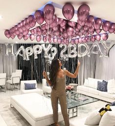 a woman standing in front of balloons that say happy birthday