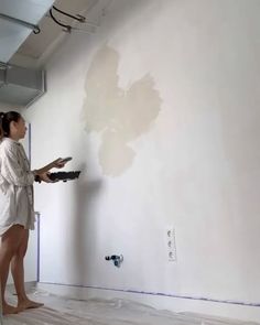 a woman in a bathrobe painting a wall