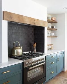 a tea kettle is sitting on top of the stove in a kitchen with blue cabinets