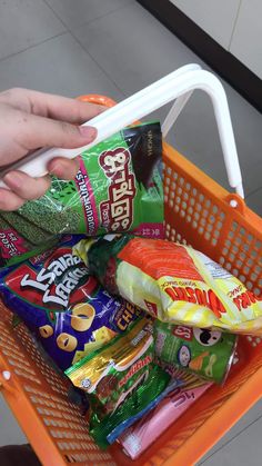 a person holding a shopping basket full of snacks