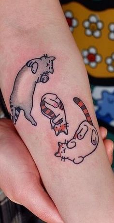 a person with a cat and dog tattoo on their left arm, both holding hands together