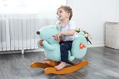 a little boy sitting on a rocking bear toy in a room with hardwood floors and white radiator